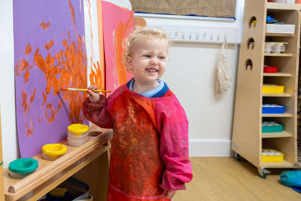 Child painting at an easel in Nursery