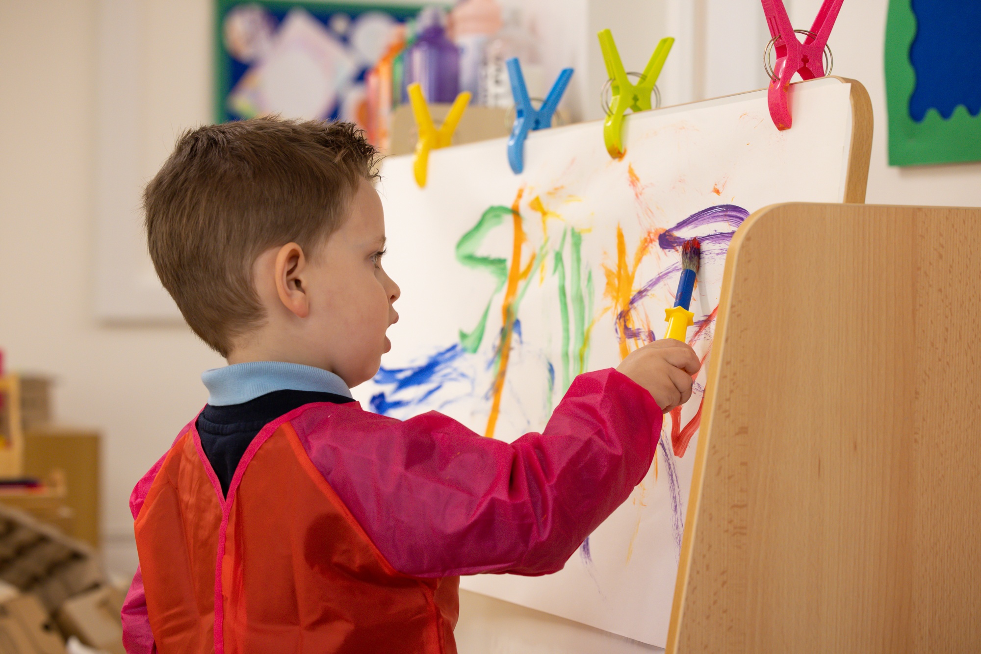 Boy in Nursery painting at easel